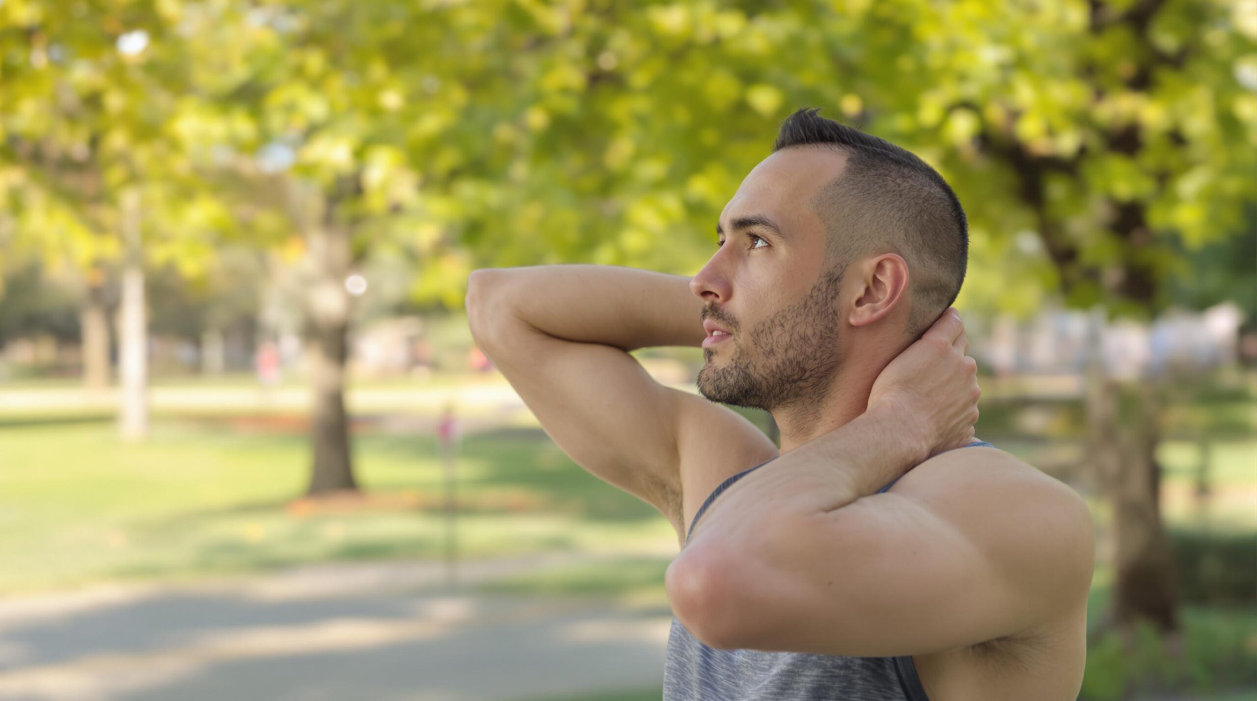 Man stretching neck in park